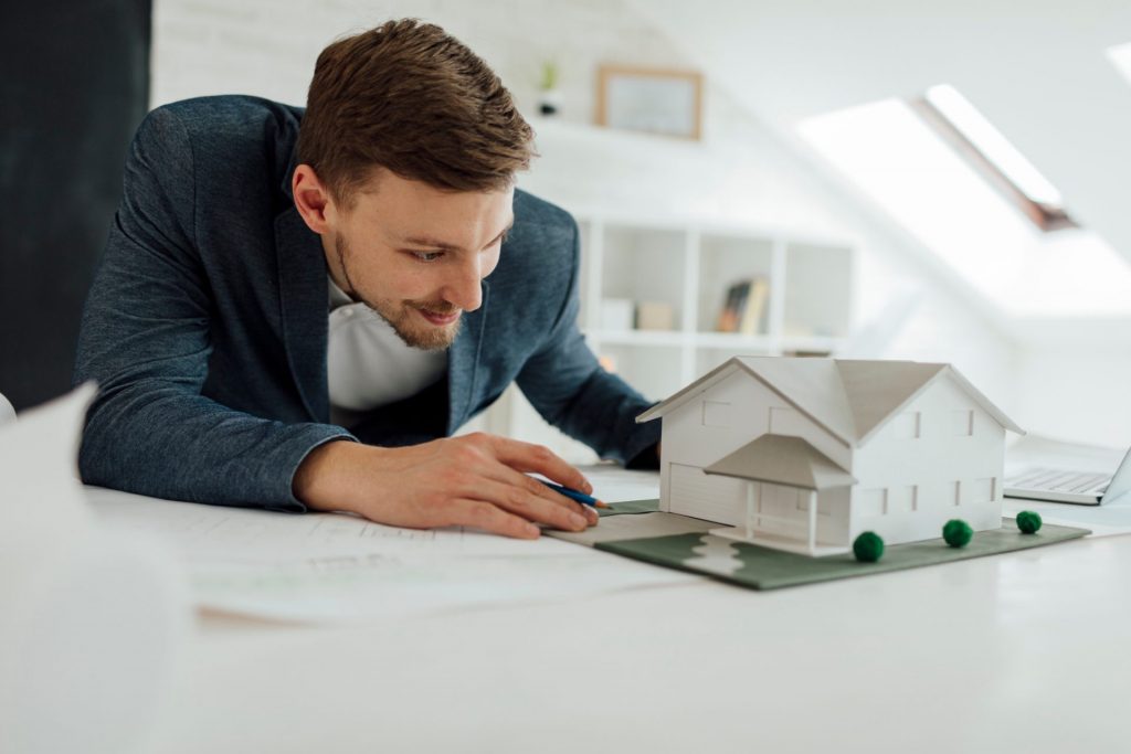 Architect reviewing architecture model of an family house in his new modern office. He is working on new project.