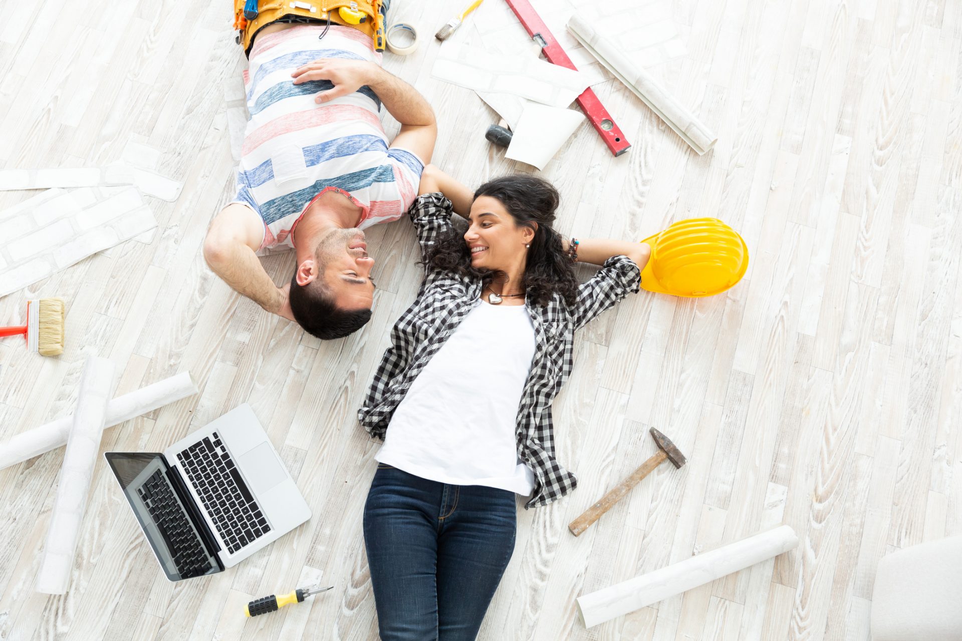 Couple making home improvement, lying down on floor, high angle view.