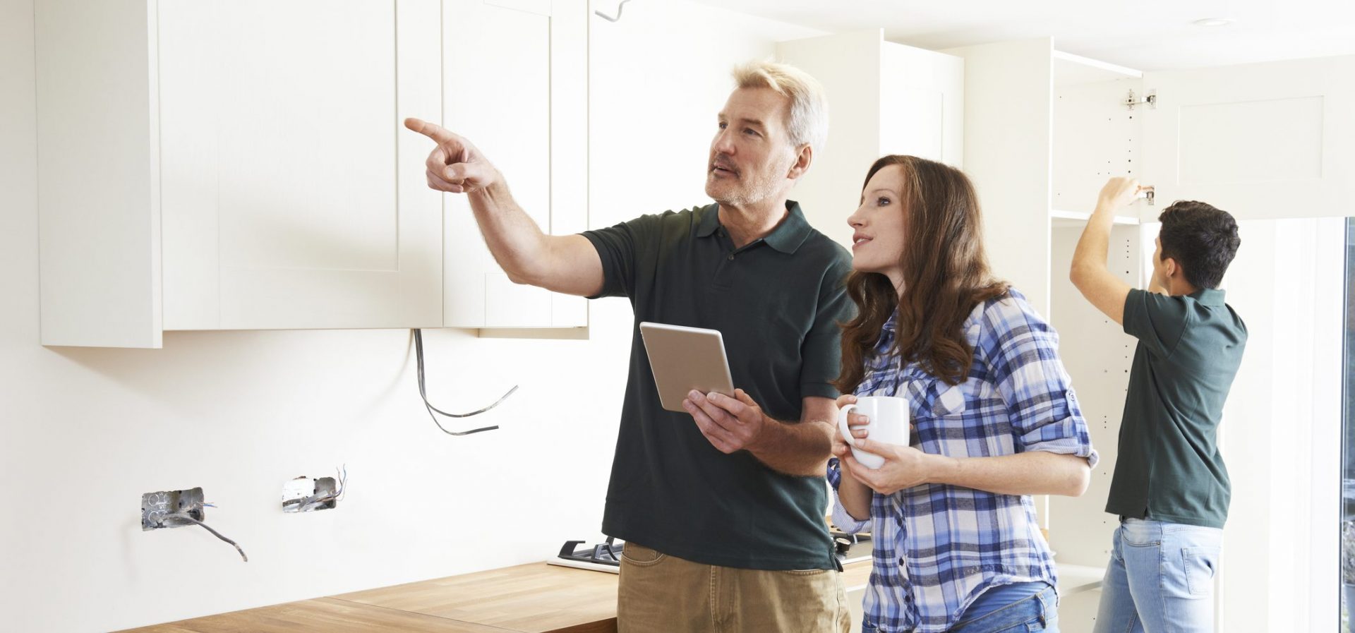 Woman With Carpenter Looking At Plans For Kitchen On Digital Tablet