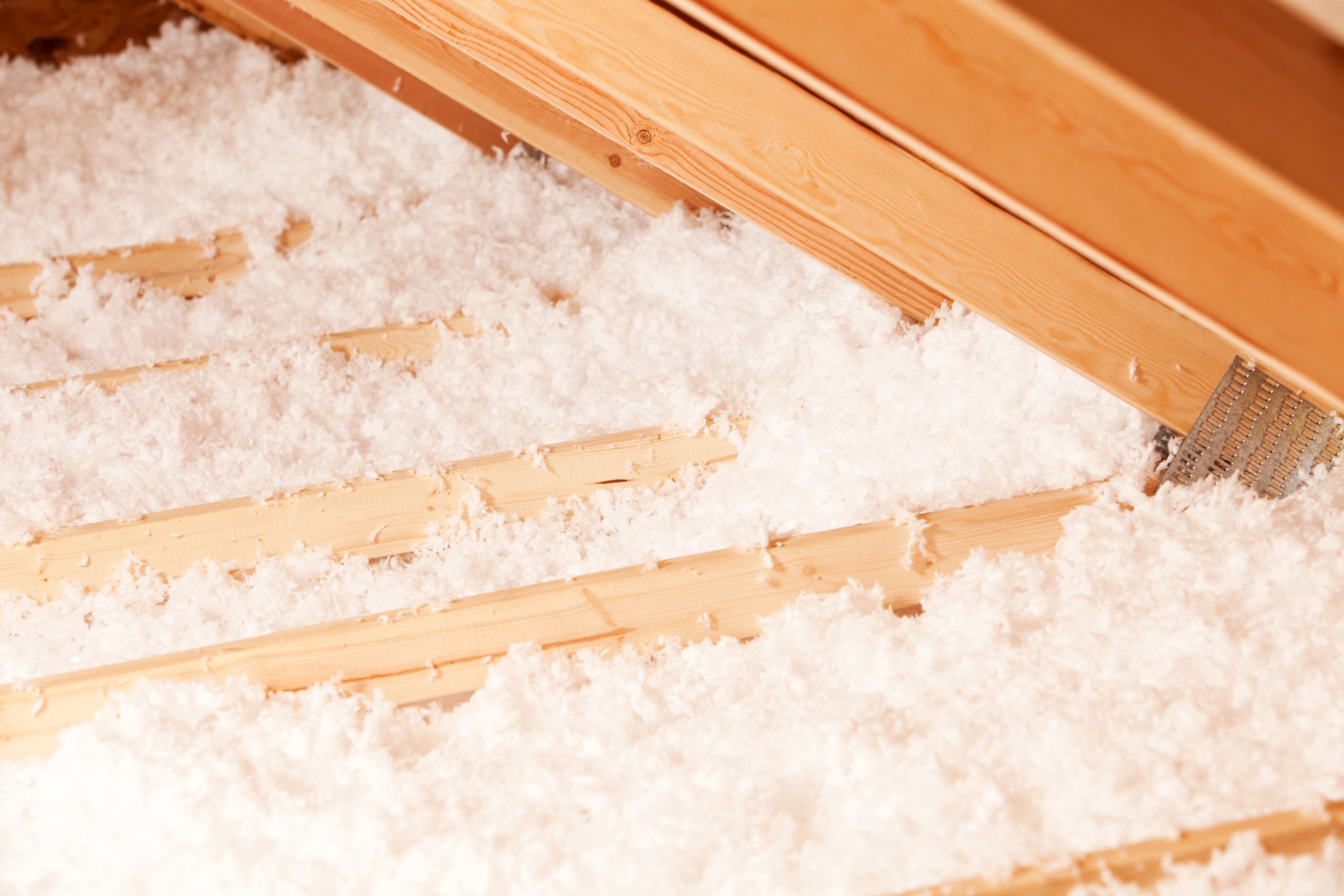 "Blown insulation between attic trusses, the angle to the right is the eave which extends beyond the house walls."