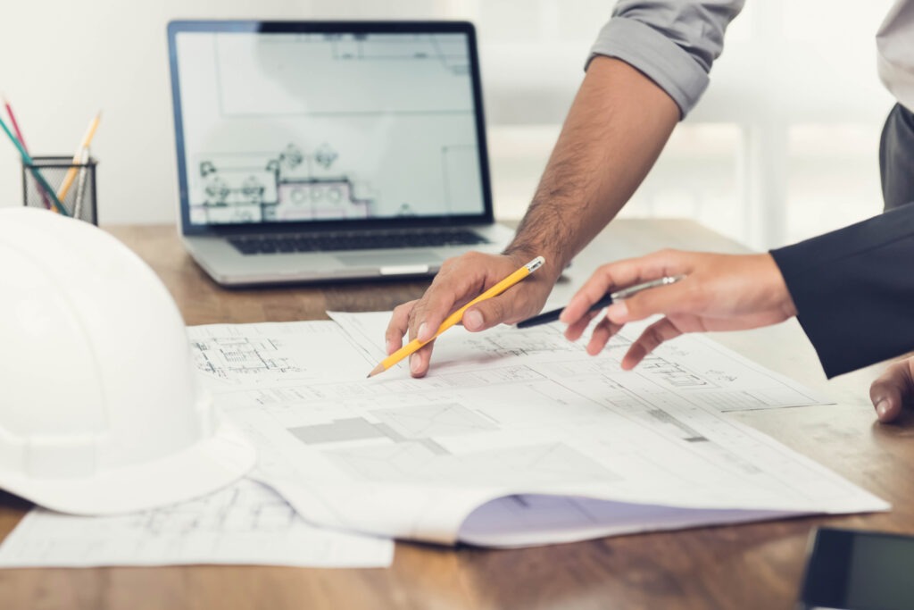 Architect or engineer team discussing a project design using blueprints and a laptop computer at the office before visiting work site.