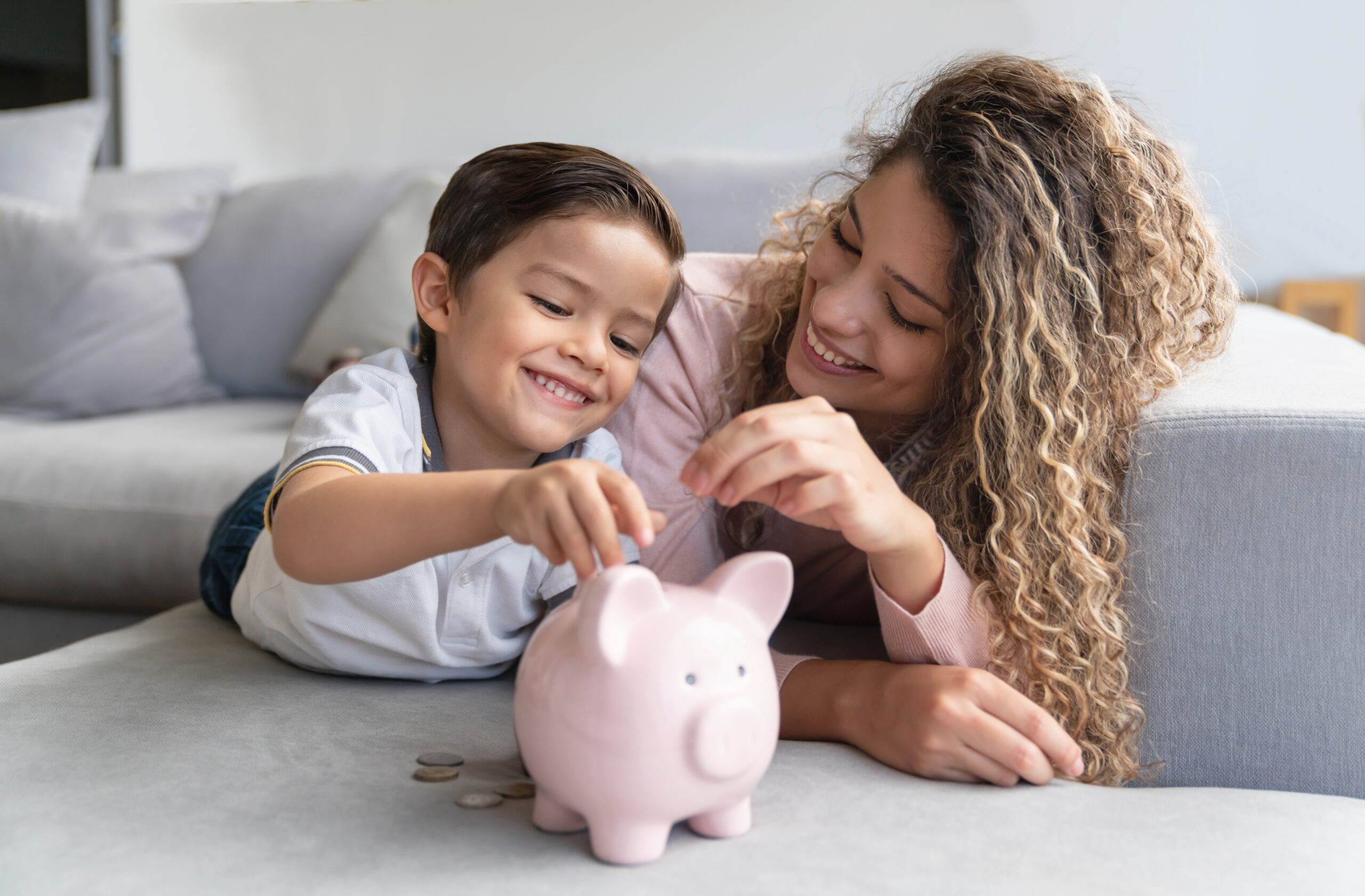 Portrait of a happy mother and son saving money in a piggybank and smiling - home finances concepts