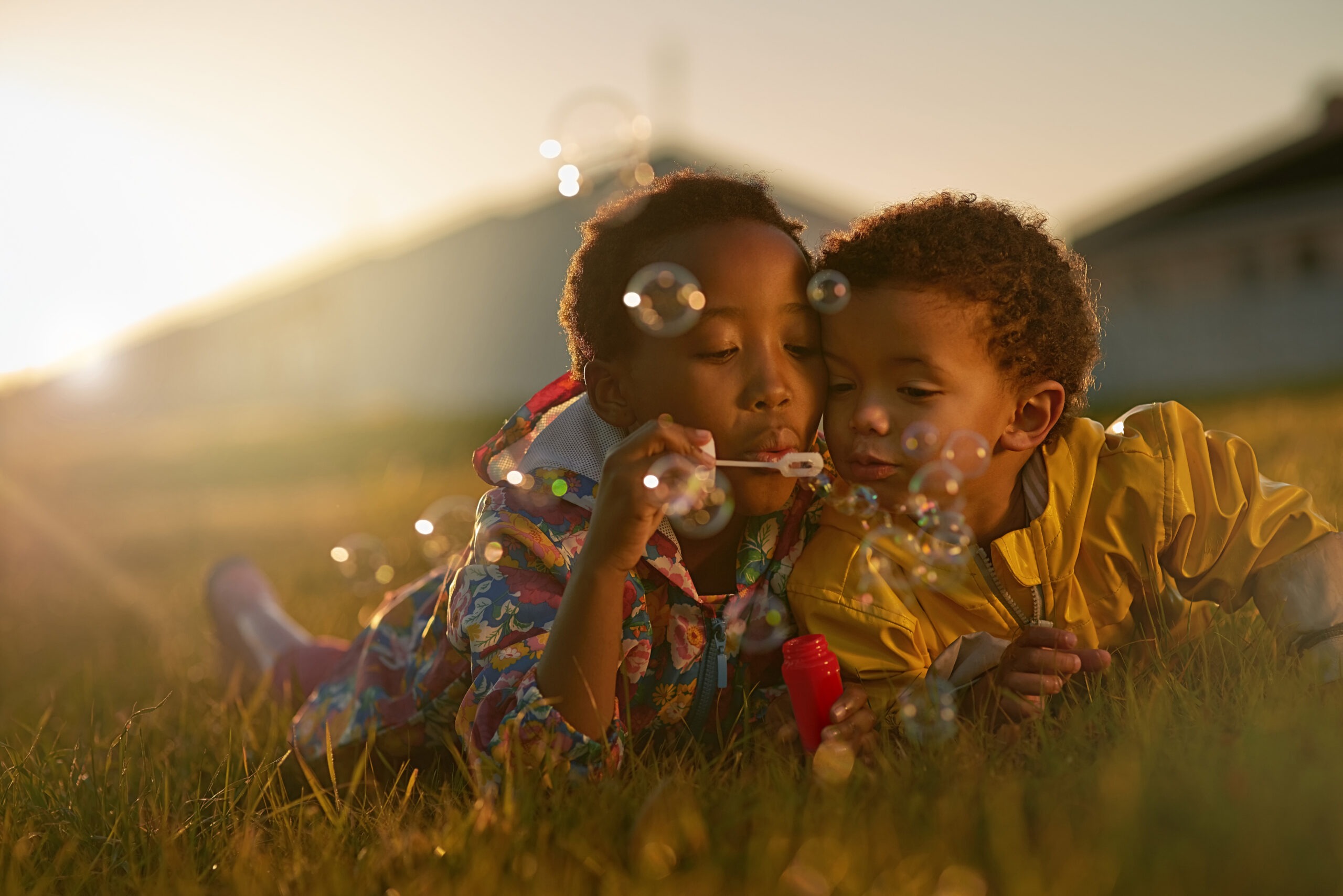 Shot of a brother and sister lying on the ground outside blowing bubbles