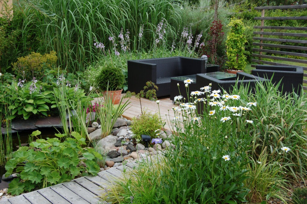 Outdoor garden lounge with a pond and a modern wicker sofa.