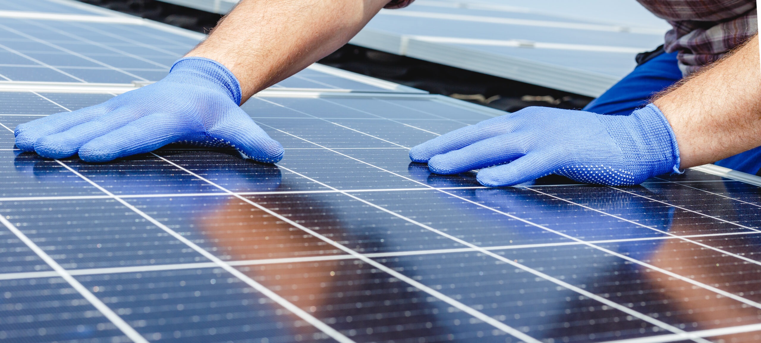 Male worker hands in glows on solar panel, technician installing solar panels on roof. Alternative energy sun energy power, ecological concept. Long web banner.