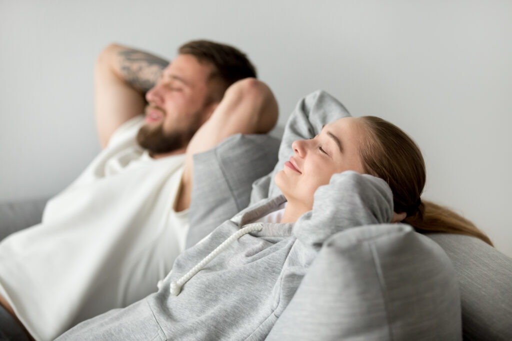 Couple heureux installé dans le canapé de leur maison neuve